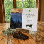 Card with mountain landscape and text on a wooden table with a window view
