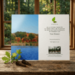 Memorial tree planting card with scenic lake and forest background on a wooden surface.